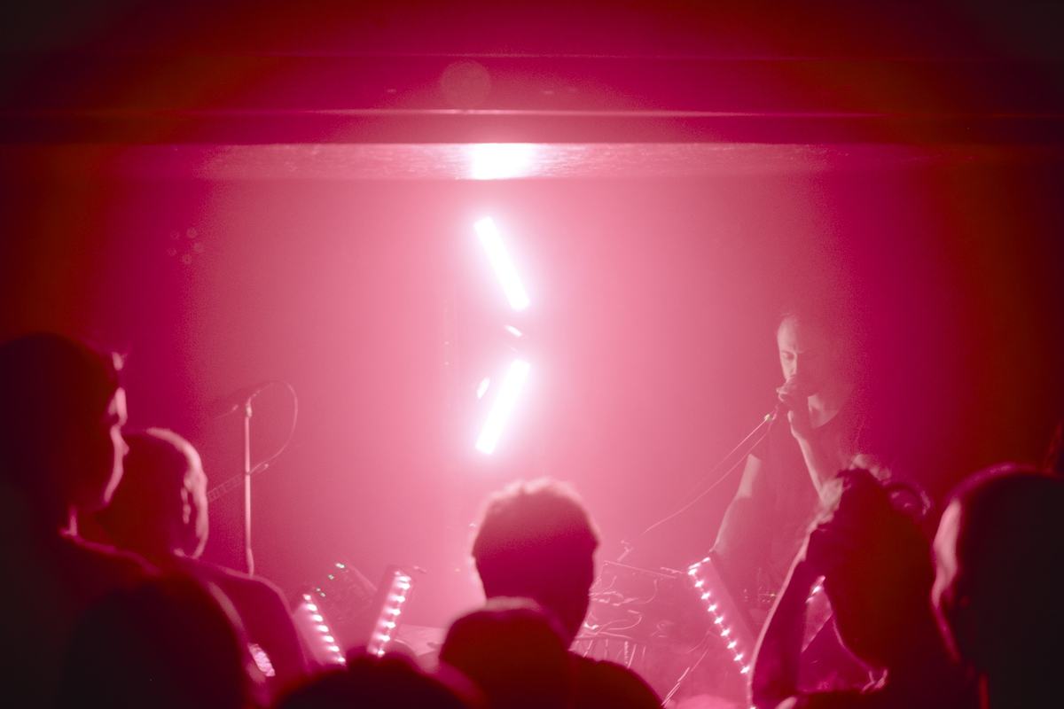 YėY performing live, view from the crowd under pink stage light
