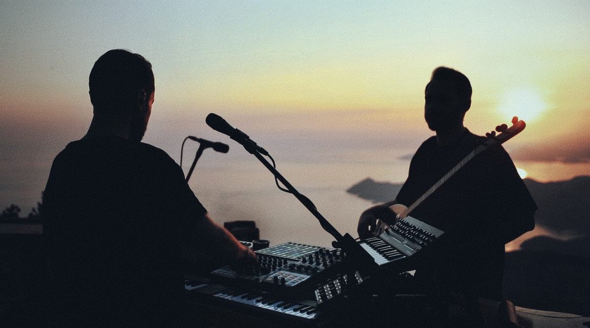 YėY performing at golden hour, silhouetted above the sea